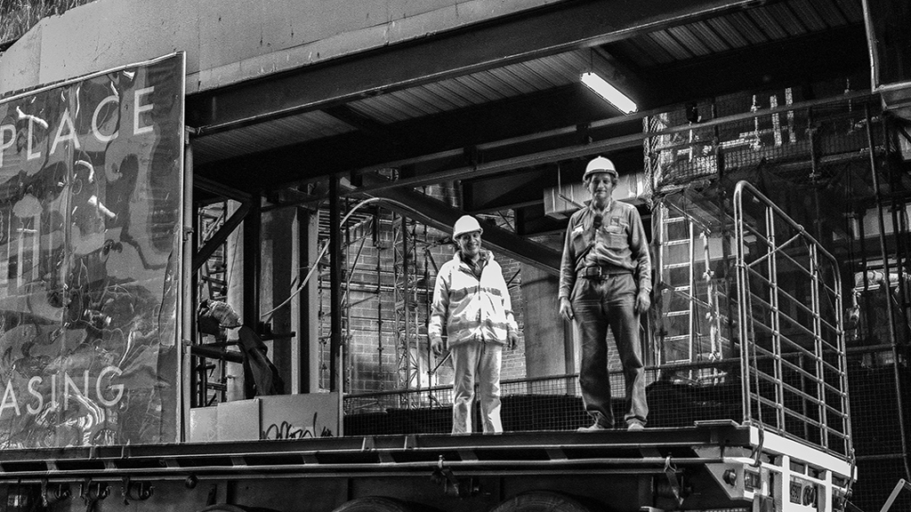 A black and white image of construction workers standing on the back of a truck on Pitt St, Sydney. Image courtesy of City of Sydney Archives, Tim Cole Collection.